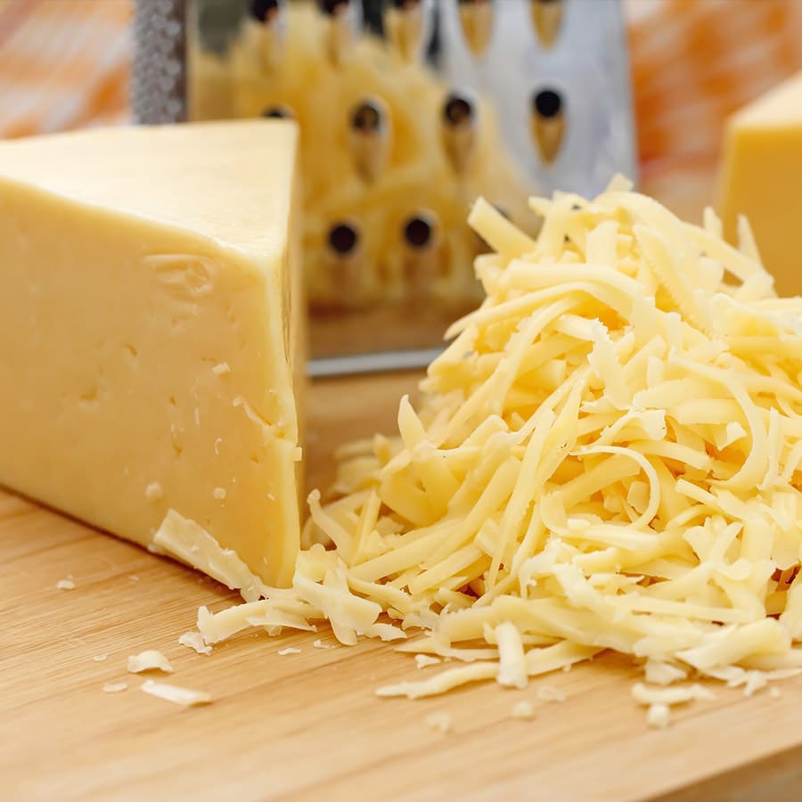 Block of cheese with grated cheese & a cheese grater